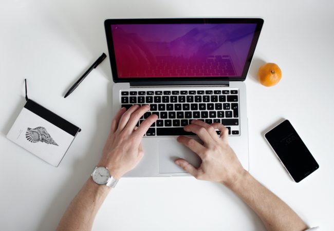 Hands typing on a silver laptop